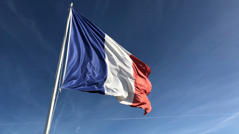 The French flag with the blue sky in the background