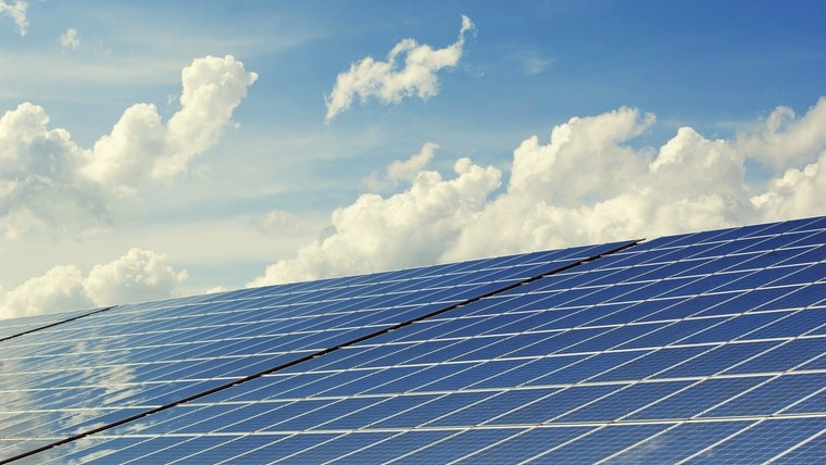 Solar panels under a cloud blue sky